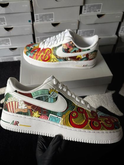 A vibrant, doodle-filled custom Nike Air Force 1 celebrating the magic of cinema, with popcorn, film reels, and 3D glasses.