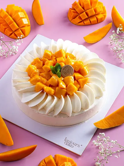 A top-down view of our Mango Cheesecake, adorned with fresh mango cubes and delicate white chocolate swirls. It's a smooth, creamy, and refreshing dessert that perfectly captures the taste of summer.