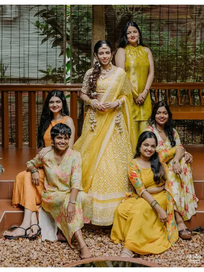 The bride and her bridesmaids, all dressed in coordinated yellow and orange outfits, share a happy moment together.