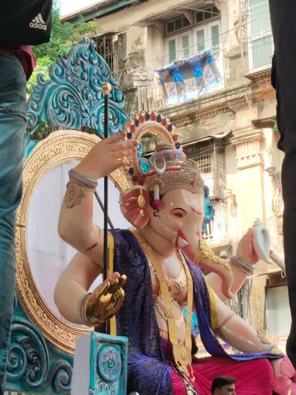 A side profile of the Kamathipura cha Mahaganpati idol during its journey. This angle highlights the idol's majestic posture and the detailed craftsmanship of the throne and ornaments.