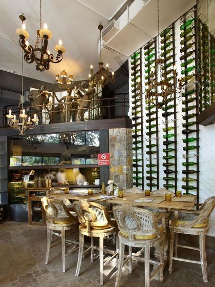 A double-height wine rack and classic chandeliers add a sense of drama and sophistication to Amour Bistro. The design blends traditional and modern elements, with a mezzanine level overlooking the main dining area.
