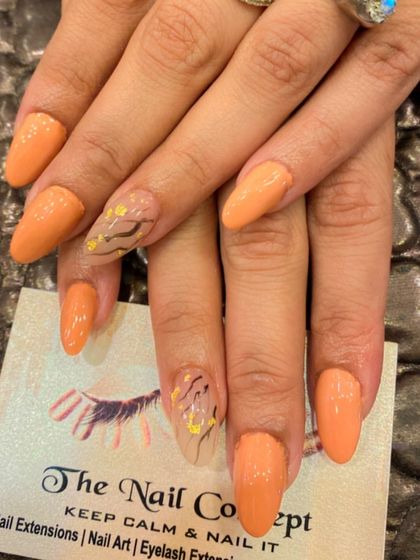A warm and subtle design on almond-shaped nails. The solid orange polish is paired with accent nails that have a sheer base and delicate, abstract line art.