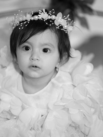 A close-up black and white portrait of a young child, her large, expressive eyes drawing the viewer in.