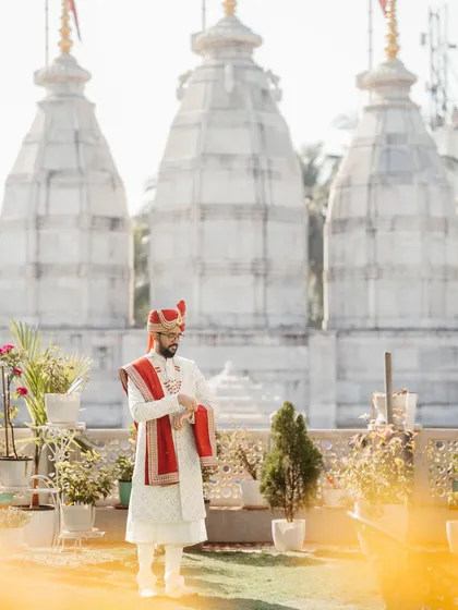 The groom in a moment of quiet reflection, with the traditional temple architecture in the background. This portrait is a beautiful blend of tradition and personal contemplation.