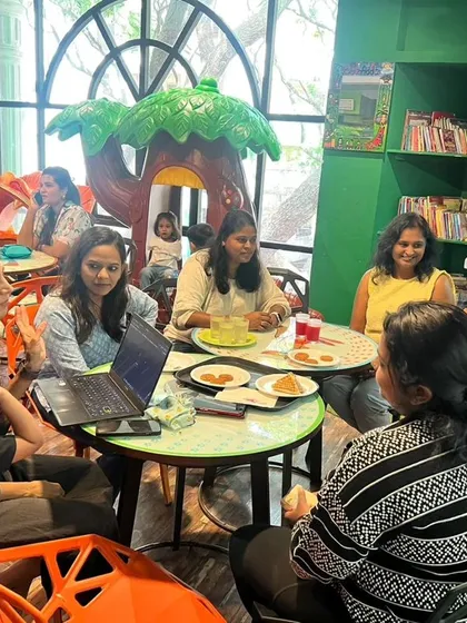 A wide shot of our café area, showing parents relaxing and chatting while their kids enjoy the play zone in the background.