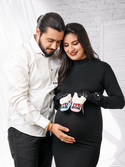 A close-up of the couple holding "I love Mom" and "I love Dad" booties over the baby bump. It’s a sweet and direct way to celebrate becoming parents.