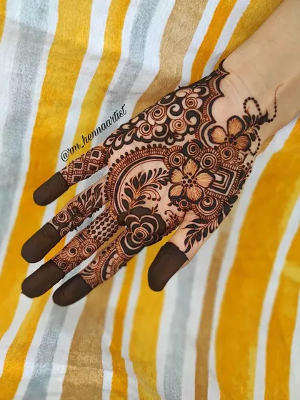 A beautiful floral design on a yellow striped background. The colours work so well together and make the henna pop.