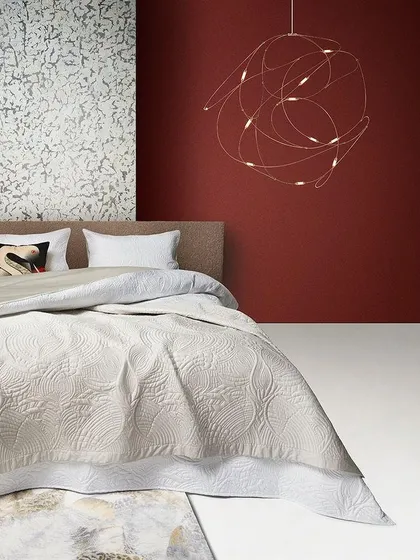 The Flock of Light by Studio Toer for Moooi, seen here as a delicate, swirling sculpture of light over a bed. It captures the magical moment of a swarm of fireflies taking flight.