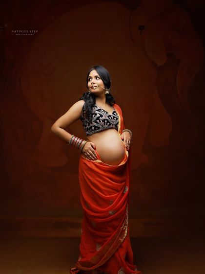A modern take on a traditional look, with the mother-to-be showcasing her baby bump in a draped saree. The elephant backdrop adds a touch of majesty.
