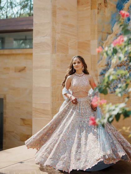 The bride twirls in her gorgeous pastel lehenga by Tamanna Punjabi Kapoor. The coral accents and mirror work catch the light beautifully, making it the perfect outfit for a festive day event.
