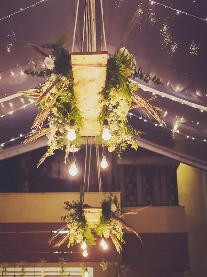 A rustic yet chic hanging chandelier we designed for a covered outdoor space. Combining wooden elements, fresh greenery, and exposed Edison bulbs, this piece adds warmth and character to the venue.