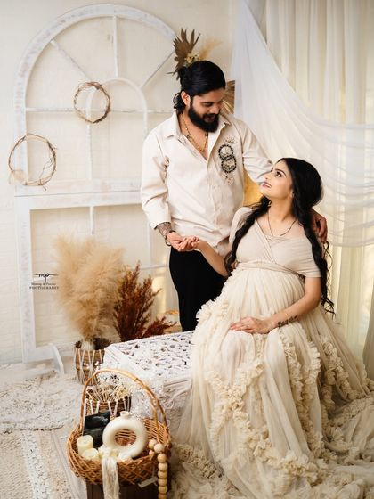 A beautiful portrait of the couple in a boho-themed studio. The husband's hand gently rests on his wife's, a simple gesture of connection and support.