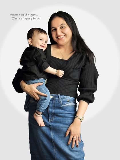 A mother holds her smiling baby, both looking happy and relaxed. This is a beautiful, classic mother-child portrait.