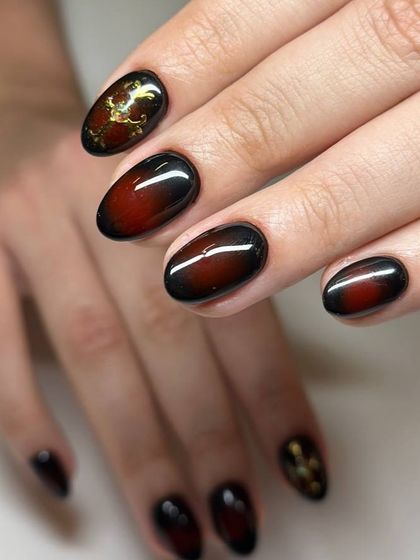 A dramatic black and red ombré cat-eye manicure. The dark, moody design is elevated with gold foil accents for a touch of luxury.