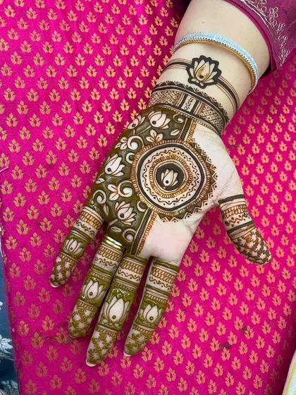 A modern take on the mandala, with a central lotus and lotus motifs on the fingers. The bracelet-style design on the wrist is a chic touch.