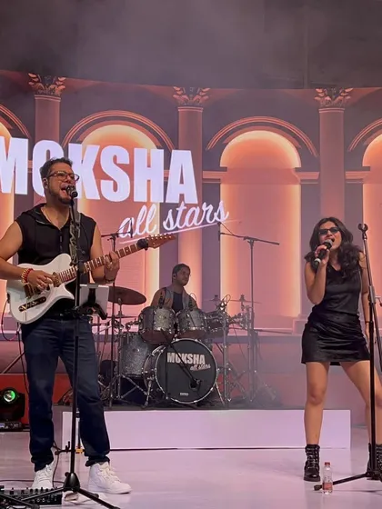 A powerful shot of me and my mentor on stage, with the Moksha All Stars logo behind us. This photo captures our dynamic as performers and the professional branding of the band.