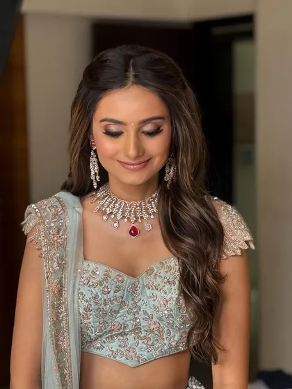 Soft, cascading waves with a simple half-up twist create a look of effortless elegance. This style is perfect for a Sangeet or engagement party.