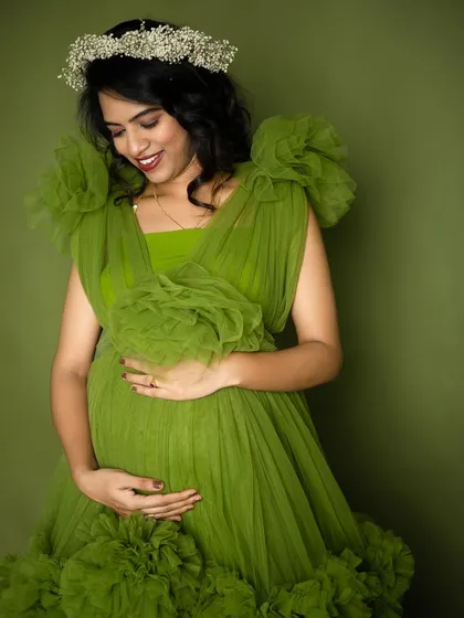 Celebrating life and growth with this beautiful mom-to-be. The vibrant green of this ruffled gown symbolizes new beginnings, perfectly complementing her radiant glow in this studio maternity portrait.