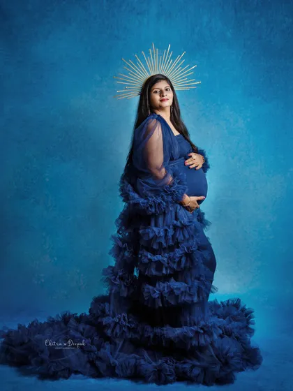 A powerful and regal portrait. The mom-to-be wears a golden halo with her navy blue gown, creating a look worthy of a queen.