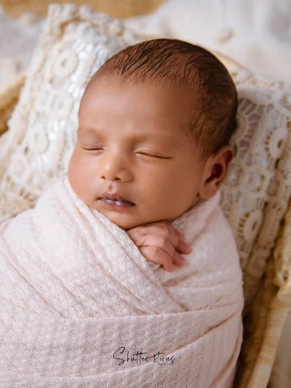 A close-up portrait of the sleeping newborn, showing the delicate details of their face and the cozy swaddle.