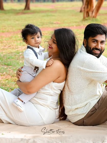 A playful back-to-back pose from the parents while their son looks on, adding a fun dynamic to the family portrait.