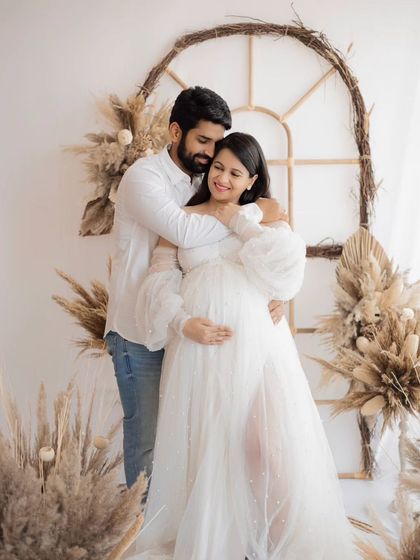 A tender embrace in our boho-themed studio setup. The natural textures and warm light create a perfect, cozy atmosphere for a couple's maternity session.