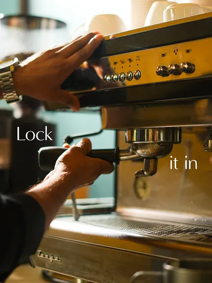 The portafilter, filled with freshly ground coffee, is locked into the espresso machine, ready for extraction.