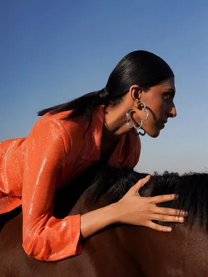 A dynamic pose of a model leaning over a horse, set against a clear blue sky. This demonstrates how our venue can be used for powerful and artistic editorial-style photography.
