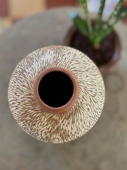 This is one of my favorite surface decoration techniques. I apply a layer of white slip over the pot and then carve through it to create these intricate, dotted patterns.