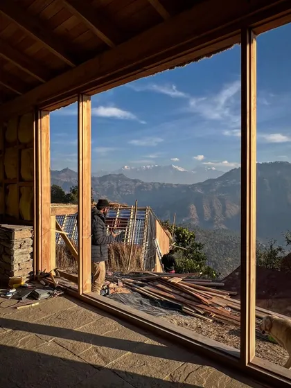 Looking out from a nearly completed guesthouse in Vasudev. The large wooden window frames are designed to capture the panoramic views of the Nanda Devi and Panchachuli peaks, making the landscape the main feature of the room.