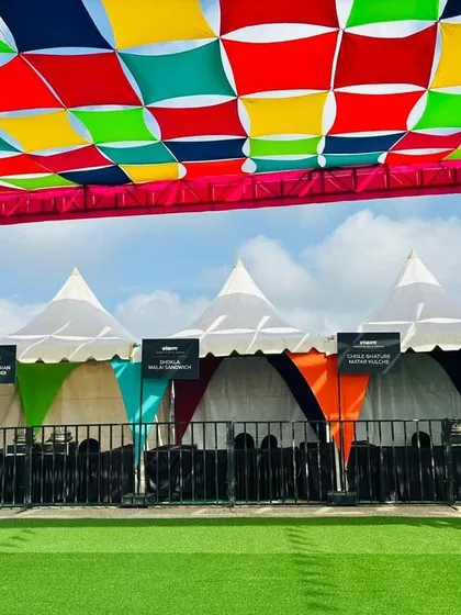 A row of neatly arranged vendor tents with a colorful overhead canopy. This shows my standard approach to creating organized, professional, and festive vendor zones.