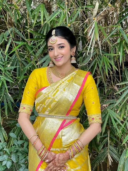 A bridesmaid in a vibrant yellow and pink Kanchipuram saree. Her custom yellow blouse is designed with subtle detailing to complement the bright and festive look.