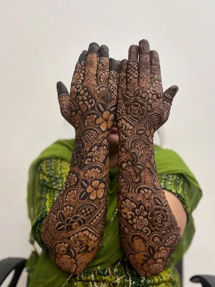 A shy bride showing off her full bridal mehndi. The design is rich with traditional patterns.