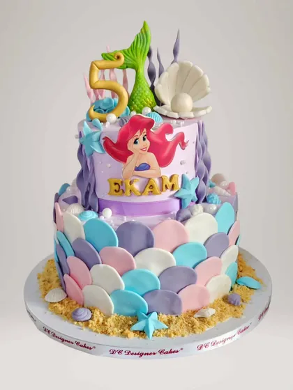 An enchanting Little Mermaid cake for a 5th birthday. This two-tier whipped cream cake features mermaid scales, seashells, and an Ariel topper, creating an underwater fantasy.