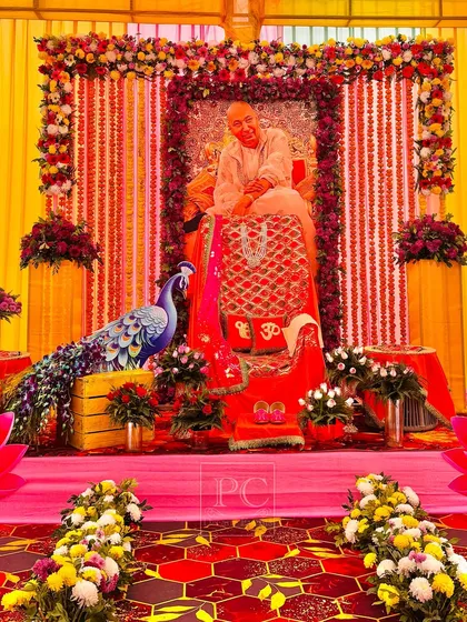 For a sacred Guruji satsang, we created this divine and opulent seating area. The decor is rich with red and yellow fabrics, extensive floral arrangements, and traditional elements like a peacock figure to create a serene and respectful ambiance.