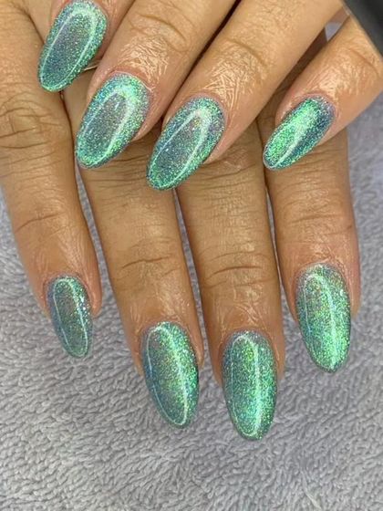 This shimmering green cat eye polish gives a magical, galaxy-like effect. The glittery, magnetic particles create a deep and captivating look on these almond-shaped nails.