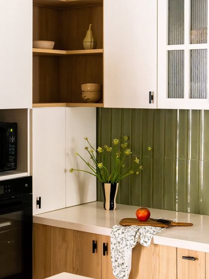 A detail shot of the modern farmhouse kitchen, showing the green backsplash, white upper cabinets, and the built-in appliance garage to keep countertops clutter-free.