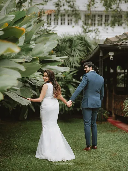 A classic "follow me" shot, as the bride leads her groom through a lush garden. A romantic and playful moment.