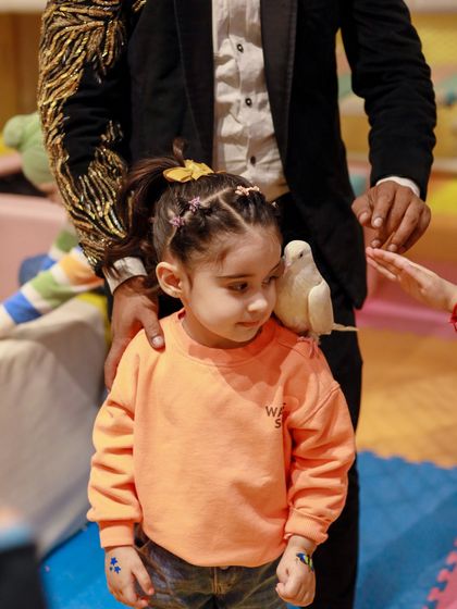 A magician introduces a gentle dove to a curious young guest. Our magic shows are interactive and safe for all ages.