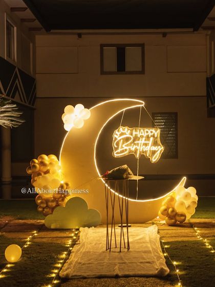 A close-up of the custom-made moon backdrop, complete with cloud cutouts and a hanging 'Happy Birthday' neon sign.