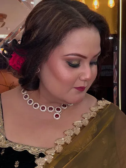 A sophisticated look for a mature client. We used warm gold tones on the eyes and a deep red lip, paired with an elegant hair bun adorned with a rose.