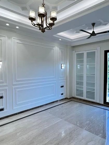 This living room is designed for both comfort and elegance. The classic wall paneling is complemented by a modern glass-paneled cabinet, providing a perfect balance for today's lifestyle.