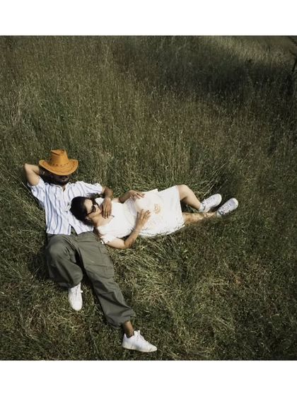 An aerial view of a couple relaxing in a field of green. This perspective adds a cinematic and peaceful feel to your pre-wedding album.