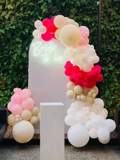 Another view of the "Bride to be" setup against a green wall. The contrast between the bright balloons and the dark foliage is very striking.