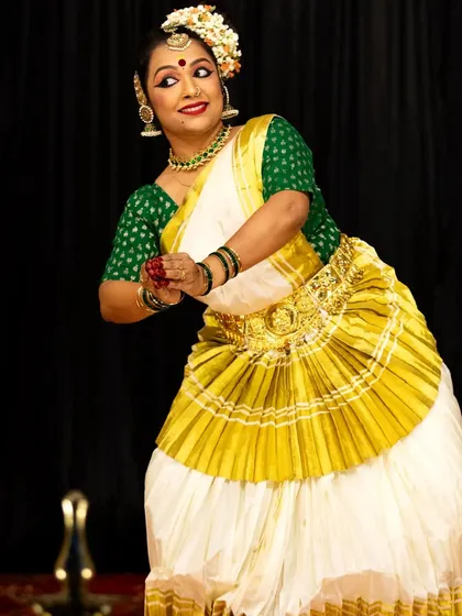 A gesture of offering during a temple performance. The traditional attire, with its iconic pleated fan, adds to the visual poetry of the dance.
