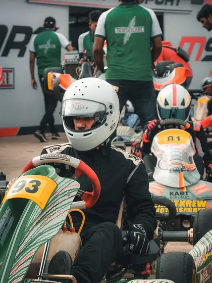 A driver in a green and white kart on the grid.