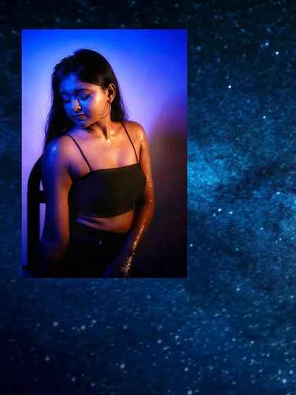 A serene portrait with the model bathed in cool blue light, her eyes closed, creating a peaceful, cosmic atmosphere.