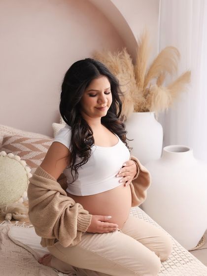 This is a portrait of peaceful connection, a mother taking a quiet moment to feel the life growing within. The soft knit cardigan and neutral tones add to the cozy, intimate feeling.