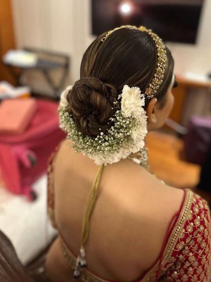 A detailed view of a classic bridal bun wrapped in a gajra of baby's breath and white carnations. This is a timeless look that I often create for brides on their wedding day.