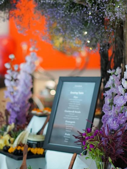 A beautifully styled grazing table set against a backdrop of purple flowers. We customize the theme and decor of our food tables to match the aesthetic of your event, whether it's a wedding, corporate launch, or private party.